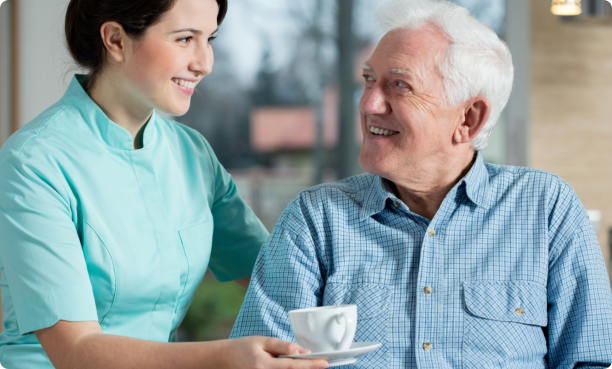 Caregiver giving coffee to old man